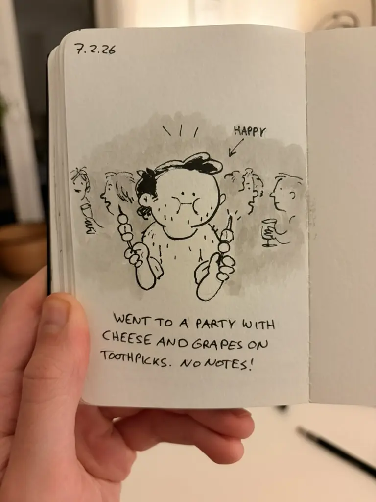 Marcel attends a party holding toothpicks with cheese and grapes.