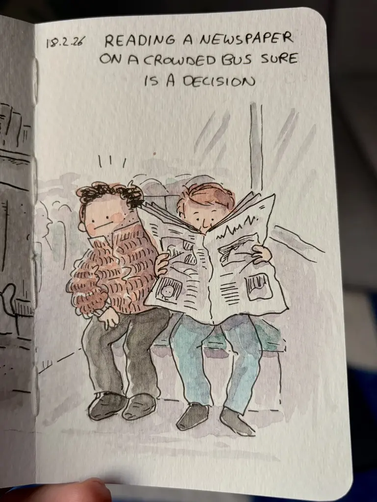 Marcel shares a newspaper with another passenger on a crowded bus.