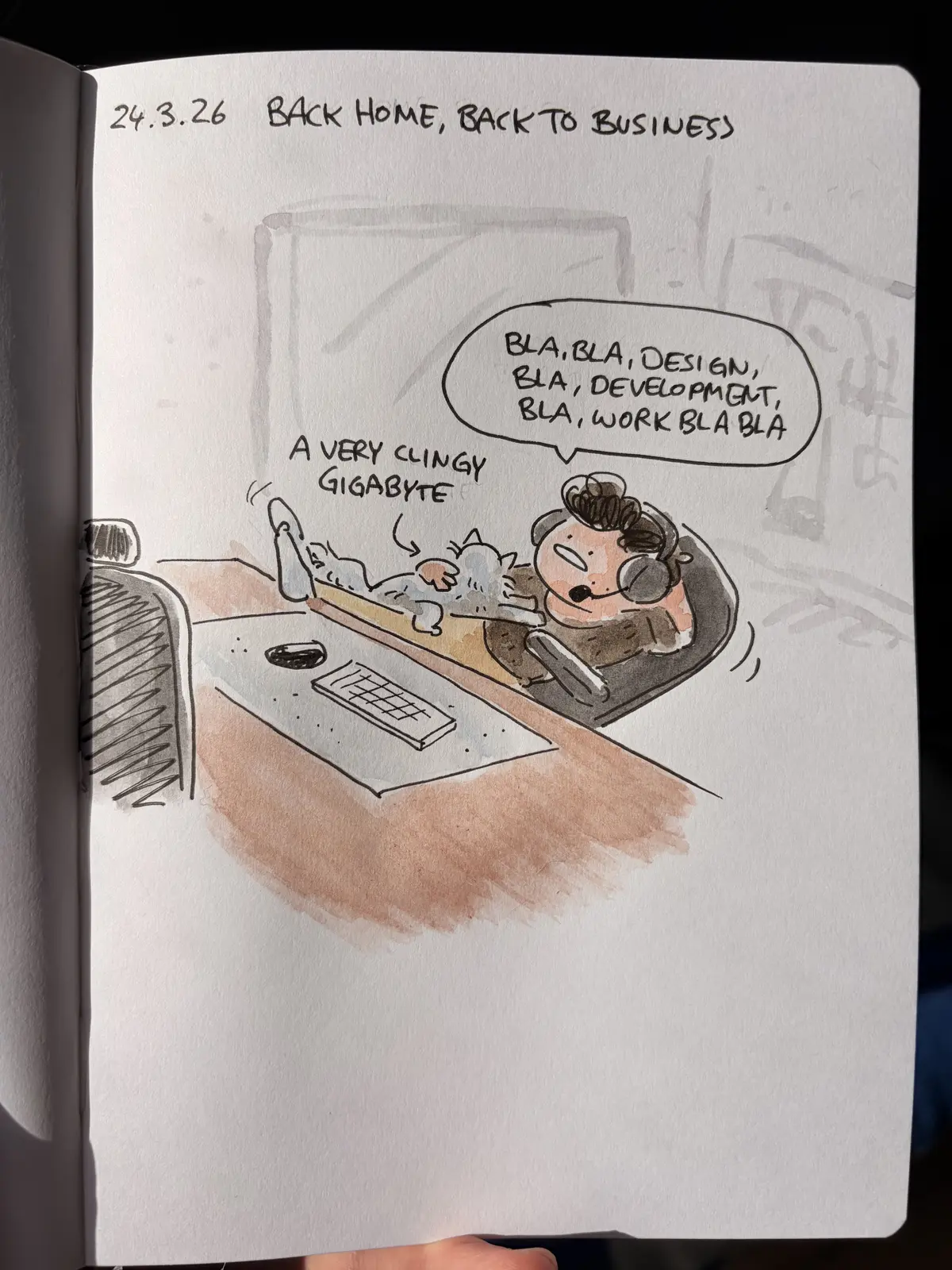 Marcel works at his computer while a clingy cat lounges across his lap.
